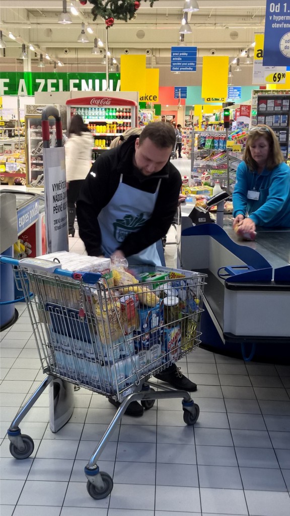 Ministr Marián Jurečka pomáhal v typické zástěře dobrovolníkům vykládat nakoupené zboží. Foto: Bps